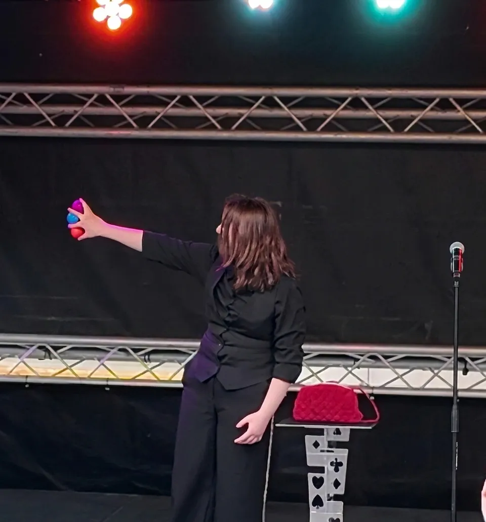 Stage Illusionist Emma williams, with coloured balls between the fingers of the left hand