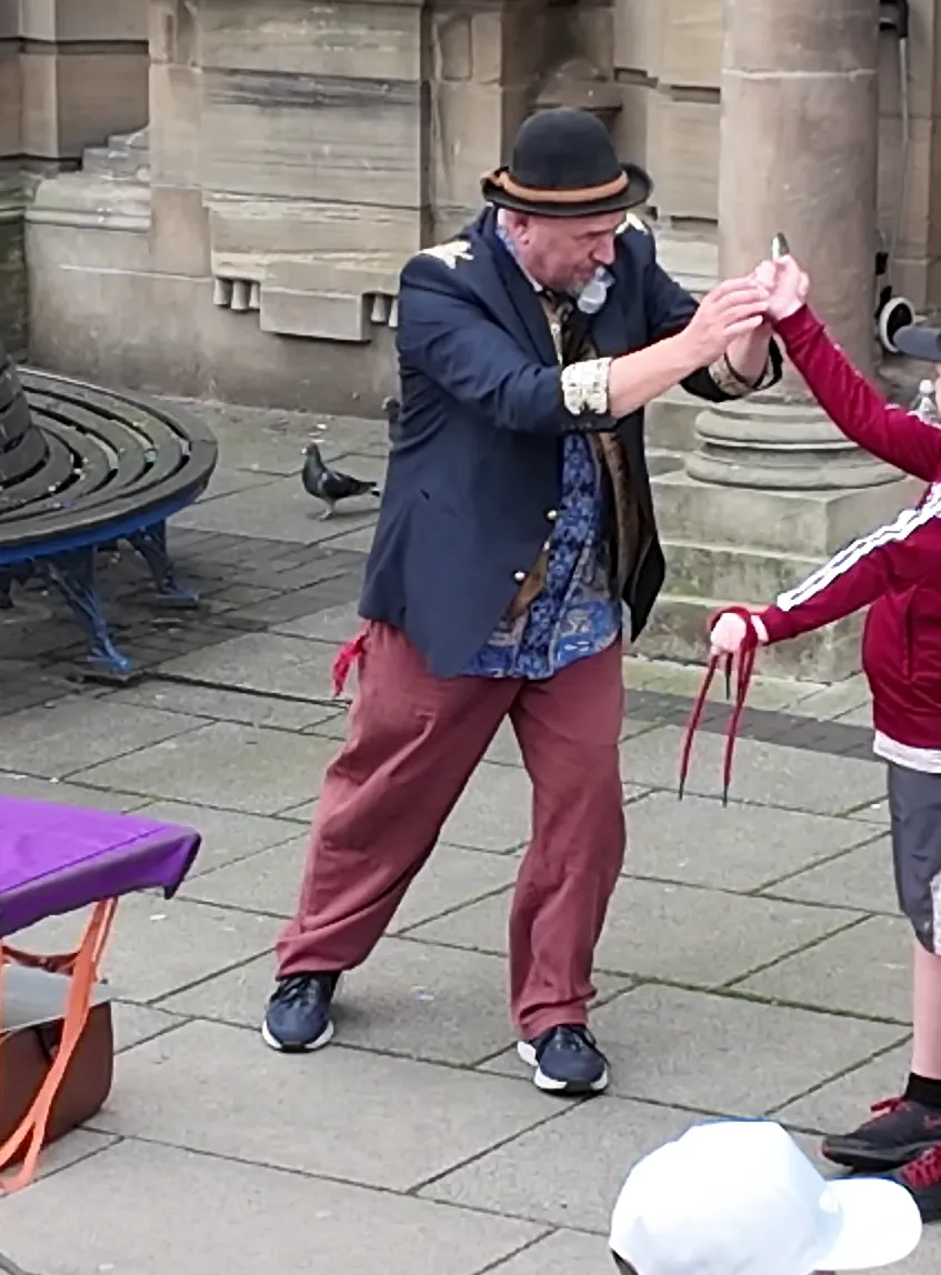 Street performer wrapping string around a spectator's hand