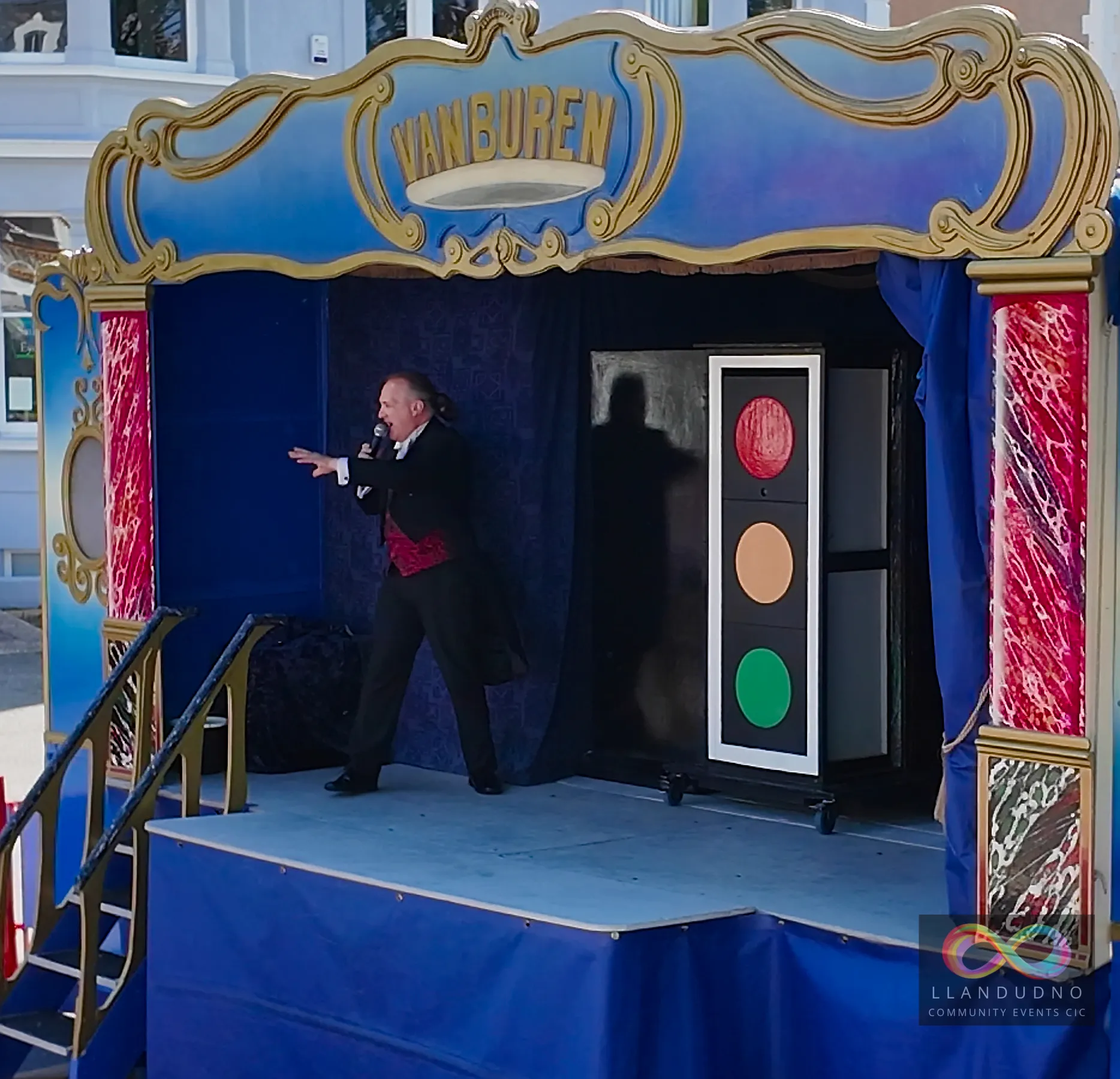 Stage illusionist with a mysterious tall box with traffic light colours